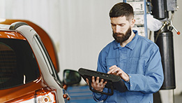 A man looking at an ipad beside a vehicle