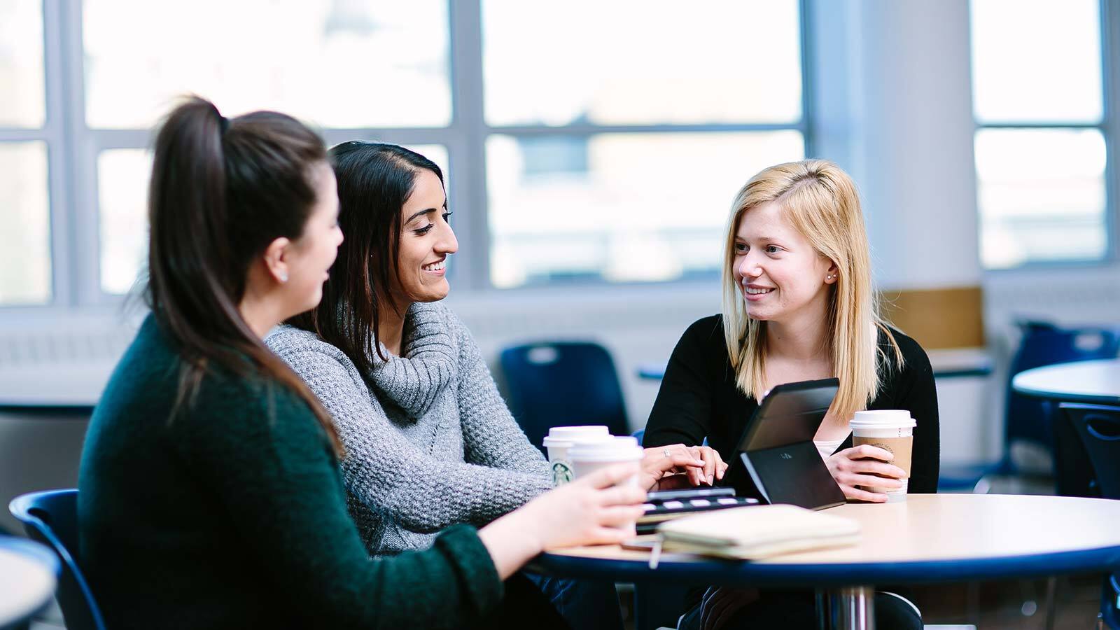 Three students chatting around a round table