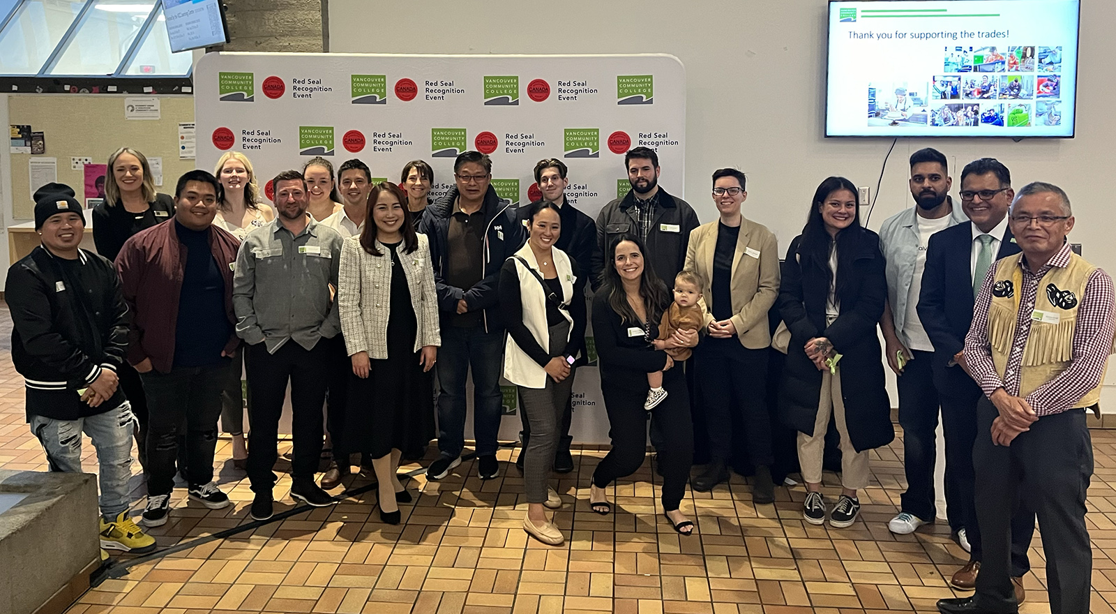 a group of VCC Red Seal alum along with VCC Faculty posing in front of a backdrop