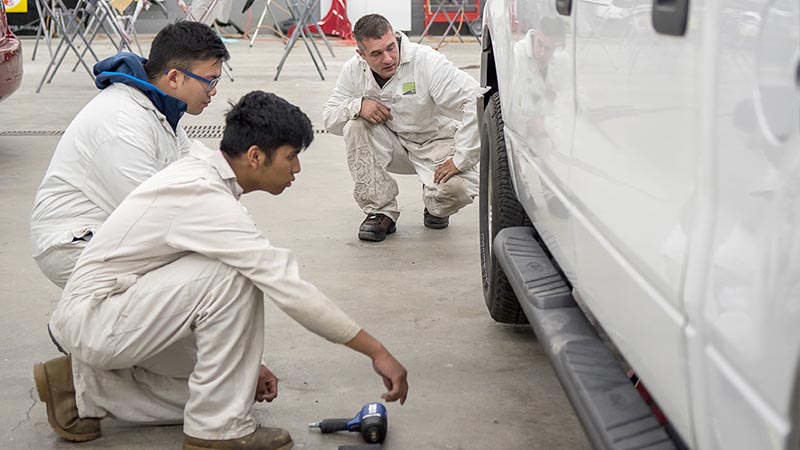 Auto students learning to assess auto body damage.