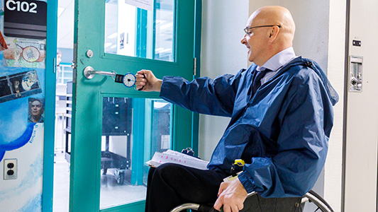 A man in a wheelchair assess the accessibility of a doorway