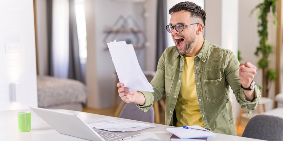 Male student looking very happy after receiving good news about financial aid.