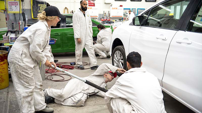 Auto students fixing cars