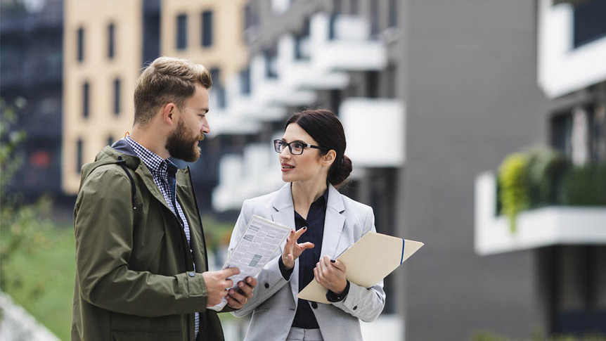 A female building manager describes paperwork to a male