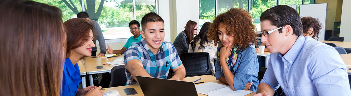 A male student leaning next to a female student, in a classroom. With microscopes, a skeleton and a Human Internal Organs Dummy in the background.